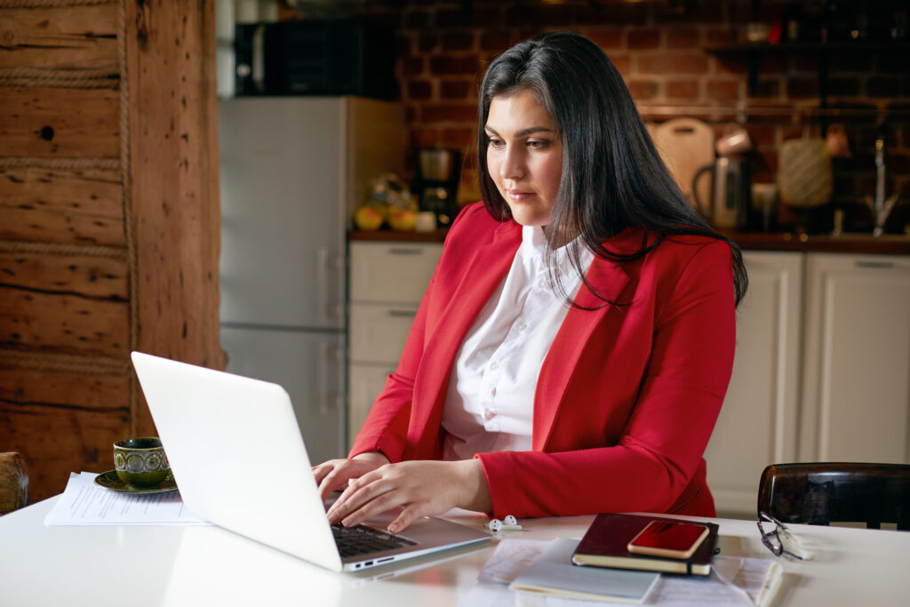 Woman working on her laptop wearing a red blazer - FASTEL high speed internet